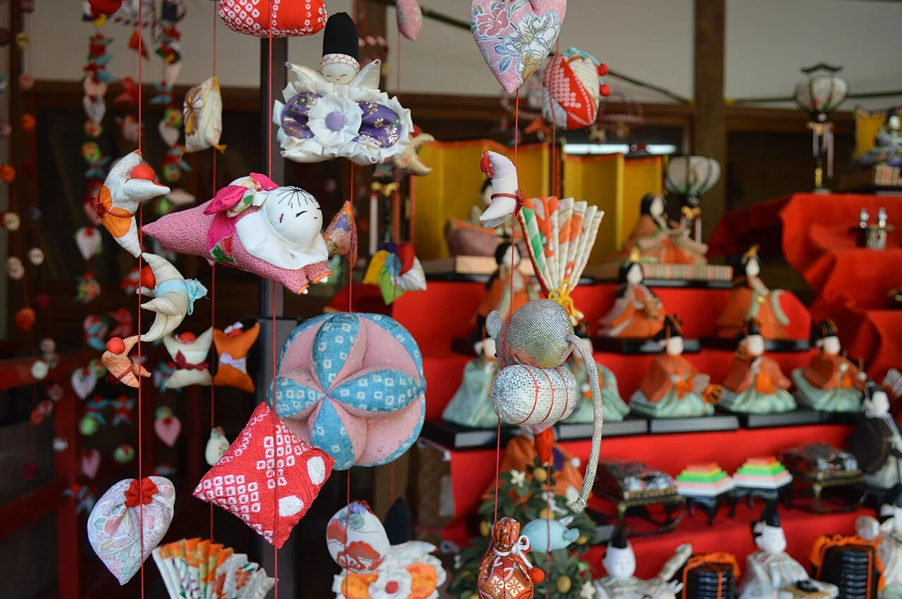 Colorful hanging fabric ornaments in front of hina dolls at Inatori Hachiman Shrine