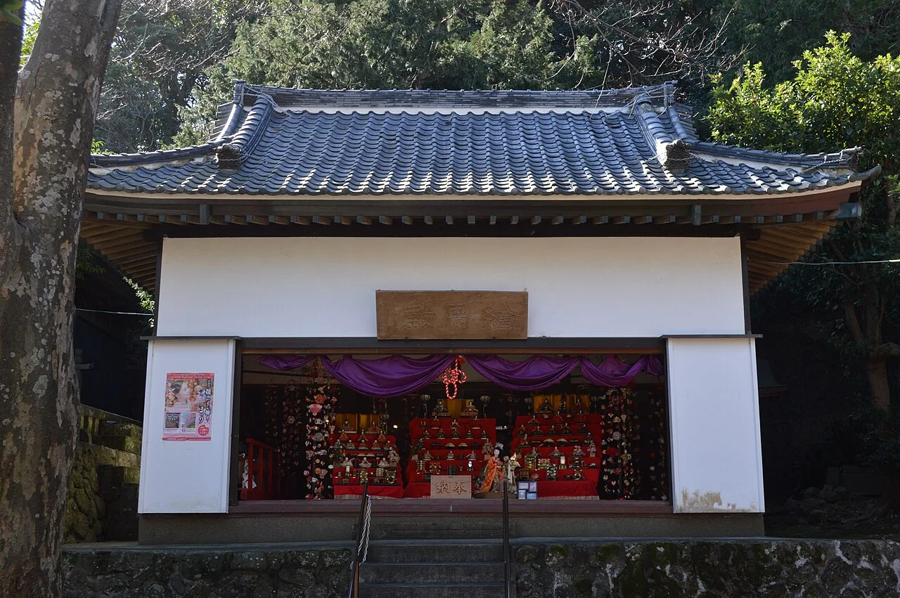 Tiled-roof shrine hall with a red hina doll display at Inatori Hachiman Shrine
