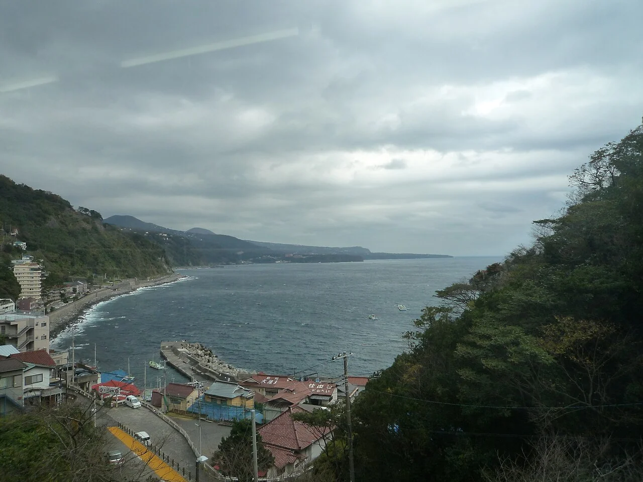 Hokkawa shoreline, small harbor and coastal buildings seen from the hillside through glass
