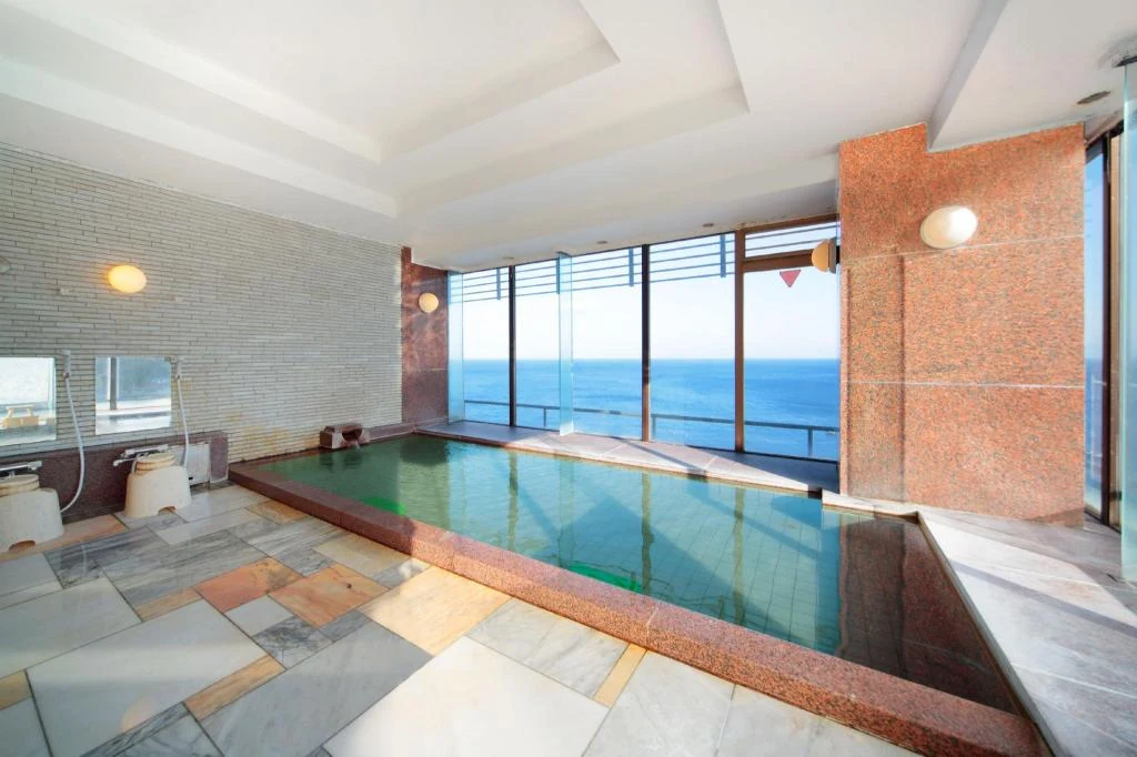 Indoor hot-spring bath with broad windows overlooking the sea at Hokkawa Onsen Hotel
